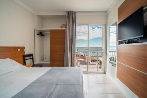 a bedroom with a large bed and a large window at Varadero Palace Hotel in Florianópolis