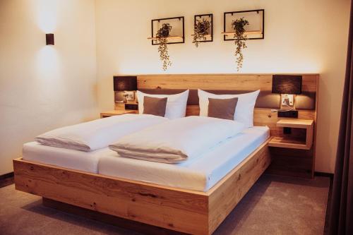 a bedroom with a large wooden bed with white sheets at Pension Sommer in Waldsassen