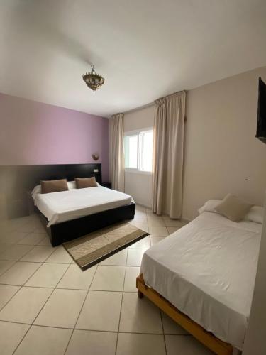 a bedroom with two beds and a window at Hotel Rama in Oued Laou