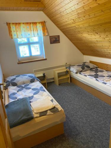 two beds in a attic room with a window at Chata u lesa in Výprachtice