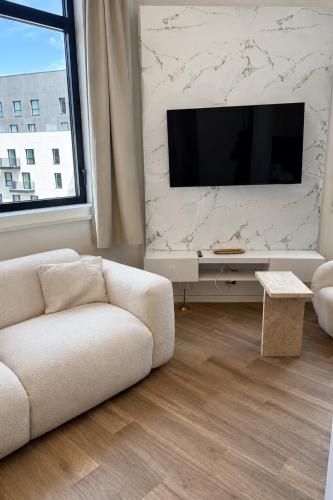 a living room with a couch and a flat screen tv at Mendess suites in Palaiseau
