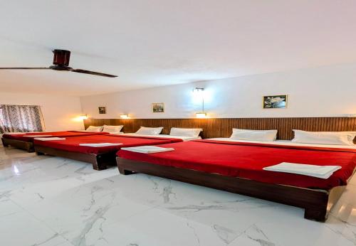 two beds in a room with red sheets at The Lantana Resorts in Madikeri