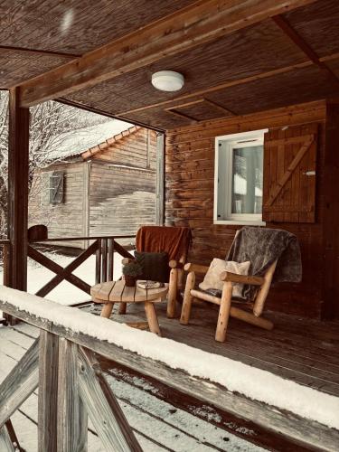 two chairs sitting on the porch of a cabin at Le Valserine - Camping éco responsable in Chézery-Forens