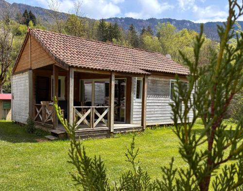 a small cabin in a field of grass with trees at Le Valserine - Camping éco responsable in Chézery-Forens