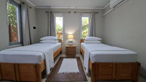 two twin beds in a room with two windows at SEMEREL APARTMENT in Palm-Eagle Beach