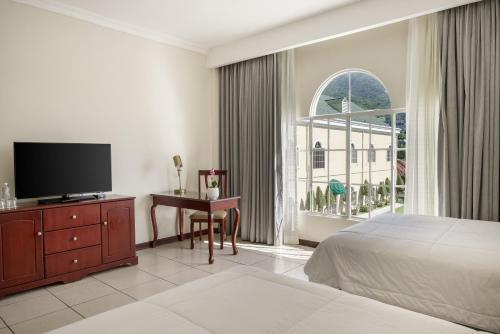 a bedroom with a bed and a desk and a tv at Hotel Mirador Plaza in San Salvador