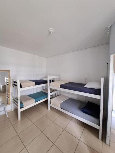 a room with three bunk beds and a mirror at Hostel Feel Home in Blumenau