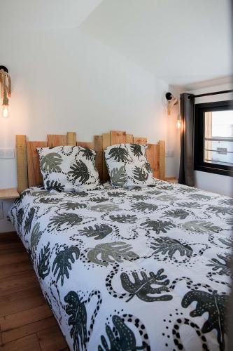 a bedroom with a bed with a black and white comforter at Les Tiny d'Aureilhan avec Jacuzzi privatif in Aureilhan