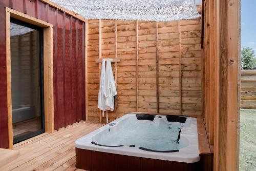 a bath tub sitting in the middle of a wooden deck at Les Tiny d'Aureilhan avec Jacuzzi privatif in Aureilhan