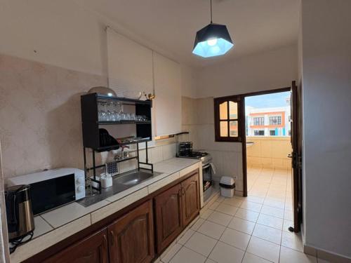 a large kitchen with a sink and a microwave at Le nid des Anges in Yaoundé
