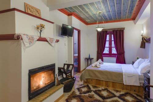 ein Schlafzimmer mit einem Kamin, einem Bett und einem TV in der Unterkunft Meliteion Traditional Hotel in Asprangeloi