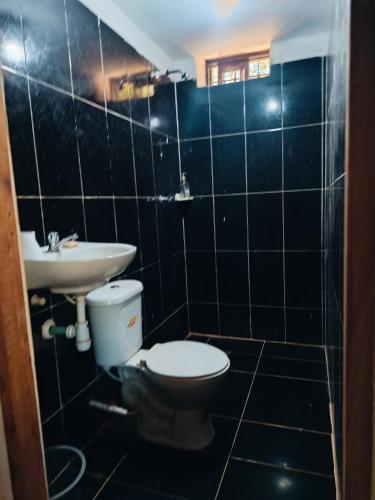 a black tiled bathroom with a toilet and a sink at Casa campo Villa Yaneth in Pueblo Bello