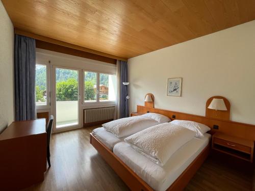 a bedroom with a large bed and a window at Parkhotel Bellevue Budget in Lenk