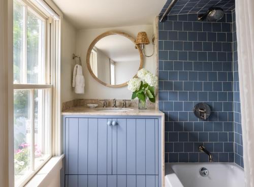 a blue tiled bathroom with a sink and a mirror at The Lightkeeper’s Inn in Edgartown