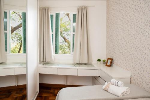 a bedroom with a bed and two windows at Bem-estar e boa localização (Apto Paraíso) in Maringá