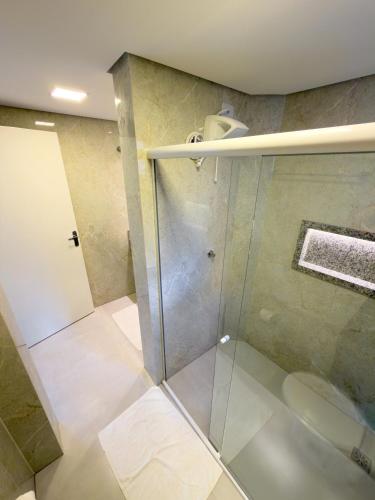 a shower with a glass door in a bathroom at Ypê Flats e Containers in Bonito