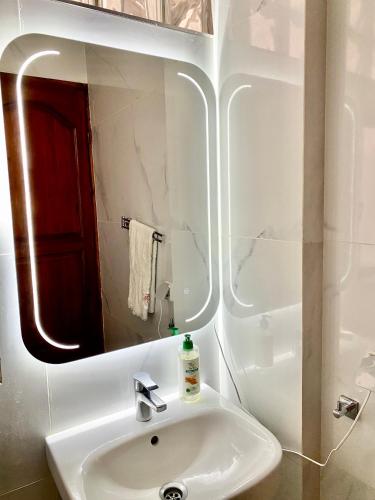 a white bathroom with a sink and a mirror at Agadir City Appartement in Agadir