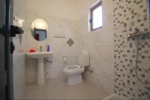 a bathroom with a toilet and a sink and a mirror at Koci Apartments in Sarandë