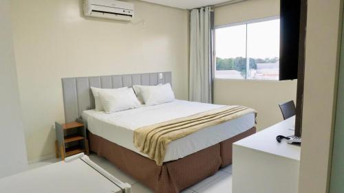 a bedroom with a bed with a desk and a window at RILL HOTEL BY UCHÔA in Teresina