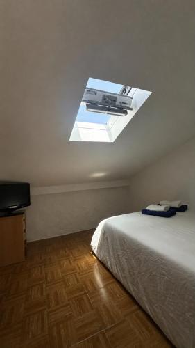 a room with a bed and a window in the ceiling at A Casa do Peregrino in A Guarda