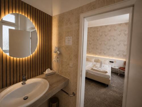 a bathroom with a sink and a mirror and a bed at Hotel Kaiserhof in Lübeck