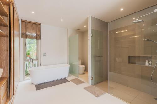 a bathroom with a tub and a glass shower at Luxury 3-Bedroom private pool villa Trichada Breeze in Phuket