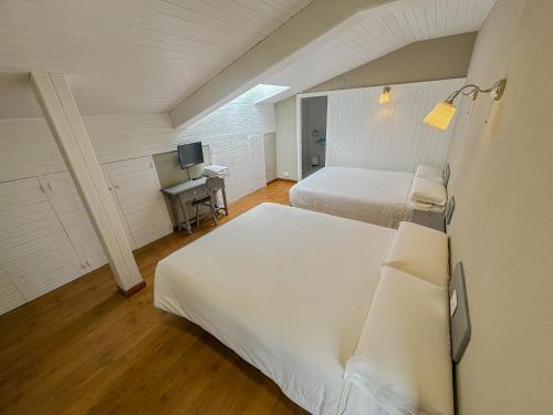 a bedroom with two beds and a desk with a television at Hotel Marqués de la Moral in Naveces