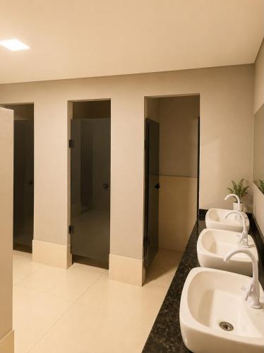a bathroom with three sinks and three toilets at Vila inn hotel in Brasília