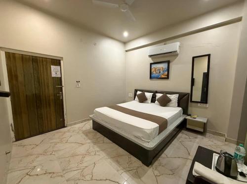 a bedroom with a large bed and a bathroom at Sariska Celebration Hotel & Resort in Alwar