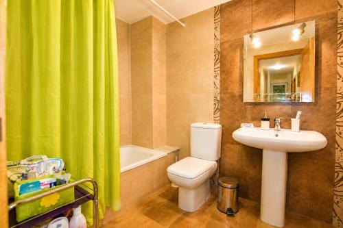 a bathroom with a green shower curtain and a toilet and sink at Apartamento Mar de Carnota in San Mamede de Carnota