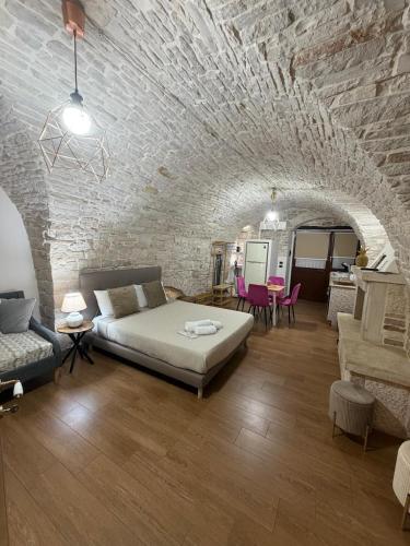 a living room with a bed and a stone wall at Casa La Grotta in Bitonto
