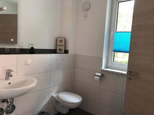 a bathroom with a sink and a toilet and a window at Ferienwohnung26 in Blankenfelde