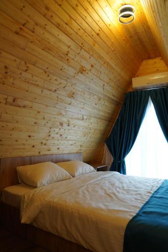 a bed in a wooden room with a window at Andrei's Refugium in Ocnele Mari