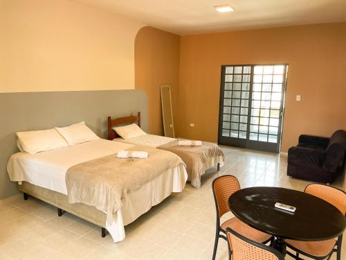 a hotel room with two beds and a chair at Hospedaria Terra da Opala in Pedro II