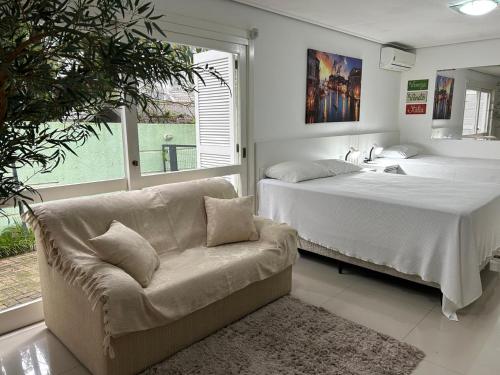 a bedroom with a couch and a bed and a sink at San Clemente Residence in Gramado
