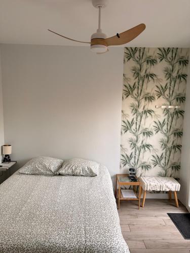 a bedroom with a bed and a palm tree wallpaper at les aulnes de sanguinet lac et piste cyclable ,5mn à pied in Sanguinet