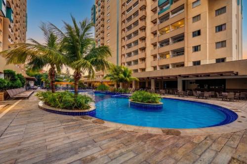 a swimming pool with palm trees and buildings at Enjoy Olímpia Park Resort in Olímpia