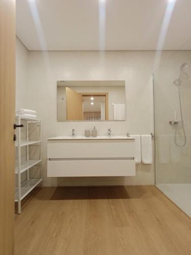 a white bathroom with a sink and a mirror at Entrecubos Apartamentos in Olhão