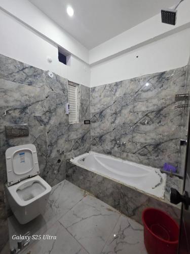 a bathroom with a toilet and a bath tub at Hotel SunFort in Rājgīr