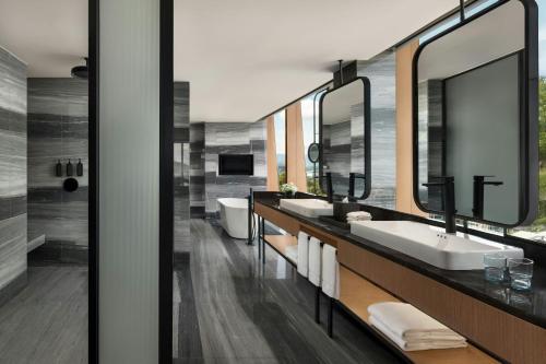 a bathroom with three sinks and mirrors and a tub at Sheraton Kota Kinabalu in Kota Kinabalu