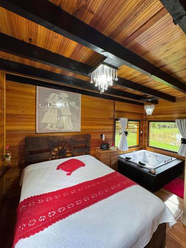 a bedroom with a bed and a tub in it at Pousada Caminho do Lago in Rio Rufino