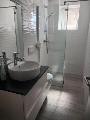 a white bathroom with a sink and a shower at Apartments Maja in Hvar