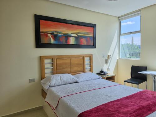 a bedroom with a bed and a painting on the wall at Hotel Portal Central in Medellín