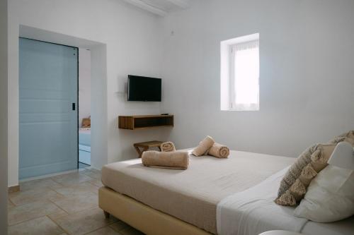 a white bedroom with a bed and a television at Casa Elia in Sarakíniko