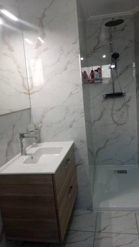 a bathroom with a sink and a shower with a mirror at Le Conviviall in Yaoundé
