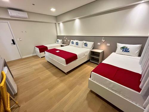 a bedroom with two beds with red and white sheets at Ody Park Resort Hotel in Iguaraçu