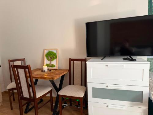 a living room with a television and a table with chairs at Leśna Przystań in Pojezierze