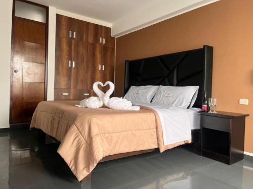 a bedroom with a bed with two swans on it at Hotel Kendari - Chincha in Chincha