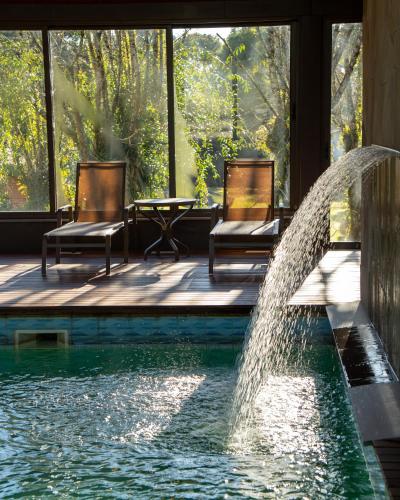 a pool with two chairs and a water fountain at Grande Hotel Canela in Canela