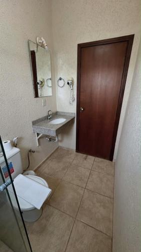 ein Badezimmer mit Toilette, Waschbecken und Tür in der Unterkunft Hotel Rafeli in Boituva